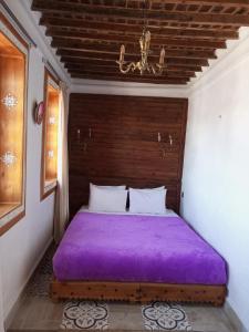 a bed with a purple blanket in a room at RIAD LA SANTA in Chefchaouene