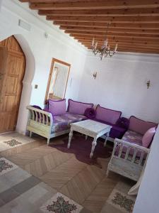 una sala de estar con sofás morados y una mesa. en RIAD LA SANTA en Chefchaouene