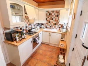 a kitchen with white cabinets and a tile floor at Waters Edge in Bakewell