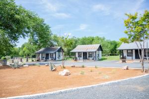 two cottages in a park with a dirt yard at THE VAQUERO MOTEL in Bandera