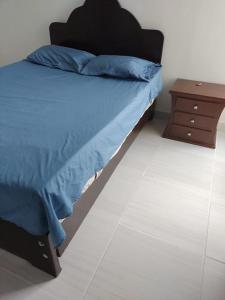a bed with a blue comforter and a night stand at Apartamento amplio y tranquilo en Flandes, Tolima in Flandes