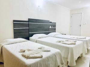 a room with three beds with towels on them at HANNA Arcos d'Atalaia Hotel - Aracaju in Aracaju