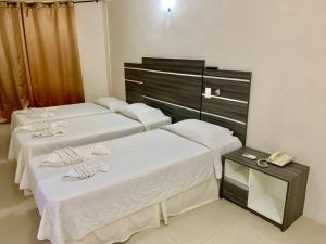 two beds in a room with a phone on a table at HANNA Arcos d'Atalaia Hotel - Aracaju in Aracaju