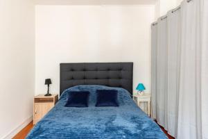 um quarto com uma cama azul e uma cabeceira preta em Charmant T2 proximité Paquebot-les Halles em Saint-Nazaire
