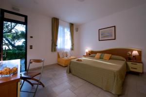 a bedroom with a bed and a table and a chair at Hotel I Ginepri in Marina di Castagneto Carducci