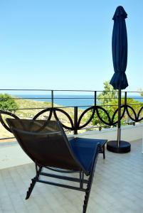 una silla y una sombrilla en un balcón con vistas al océano en Magnificent sea view,clean and bright apartments, en Kalathas