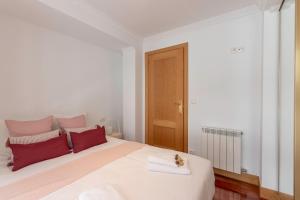 a bedroom with a large white bed with red pillows at Plazuela Sta Catalina I en Mundaka By Kabia Gestión in Mundaka