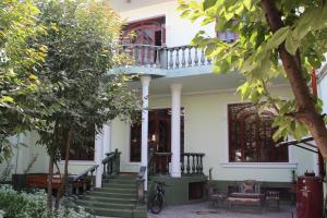 une maison blanche avec des escaliers et un balcon. dans l'établissement Green House Hostel, à Douchanbé