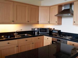 a kitchen with wooden cabinets and a sink and a microwave at Pass the Keys Classy 2 bedroom apartment amazing beach views in Torquay