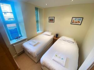 two beds in a small room with two windows at Pass the Keys Classy 2 bedroom apartment amazing beach views in Torquay