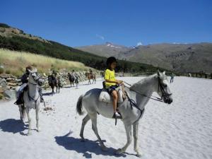 ein kleines Kind reitet auf einem Pferd am Strand in der Unterkunft Sierra Nevada Home in Sierra Nevada