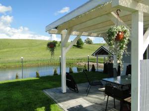 a white pergola with a table and a pond at Cztery Pory Roku in Gołdap