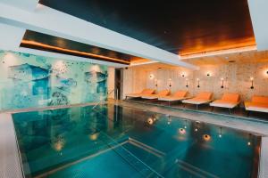 a swimming pool with orange chairs in a building at Alpin - Studios & Suites in Warth am Arlberg