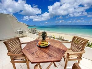 - une table en bois avec un bol de fruits sur la plage dans l'établissement Paradis Caraibes 1, feet in the water in Grand Case, à Grand-Case
