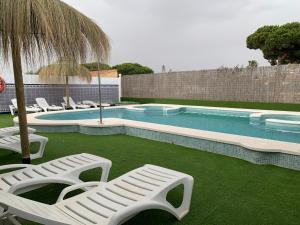 a swimming pool with lounge chairs and an umbrella at Apartamentos Costa Luz in Matalascañas