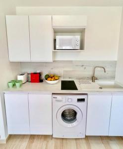 a white kitchen with a washing machine and a sink at Maracuja 17, Orient Bay village, walkable beach at 100m in Orient Bay