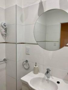 uma casa de banho branca com um lavatório e um espelho em Departamentos Fleming, luminosos p hasta 4 personas em Paraná