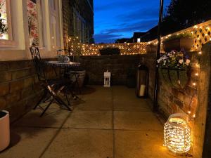 a patio with christmas lights and a table and chairs at Cute and cosy 2 bed cottage in Honley
