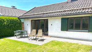 un patio con sillas y una mesa frente a una casa en Bungalow in Rottachs Bestlage en Rottach-Egern