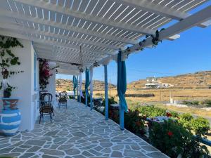 a white pergola with chairs and tables on a patio at Mihaela Apartments Sifnos in Faros