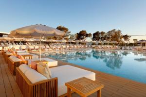 a swimming pool with tables and chairs next to a resort at TRS Ibiza Hotel - Adults Only in San Antonio