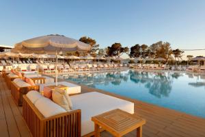 una piscina con mesas y sillas junto a un complejo en TRS Ibiza Hotel -All Inclusive Adults Only, en San Antonio