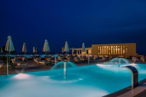 a pool at night with chairs and umbrellas at Ammoa Luxury Hotel & Spa Resort in Nikiti