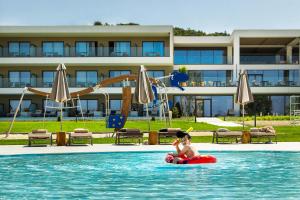 a young child in an inner tube in the water at a resort at Ammoa Luxury Hotel & Spa Resort in Nikiti
