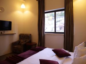 um quarto de hotel com uma cama e uma cadeira e uma janela em Twins Downtown Hotel em Amã