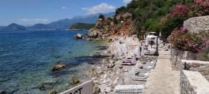 a beach with white lounge chairs and the water at Residence Vukovic, Rezevici in Reževići