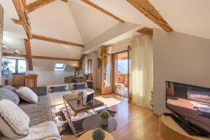 a living room with a couch and a tv at Charmantissime appartement avec vue montagnes - 3 ch, LLA Selections by Locationlacannecy in Saint-Jorioz