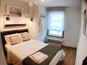 - une chambre avec un lit doté de draps blancs et une fenêtre dans l'établissement Apartamento estilo costero al lado de la playa, à Goyanes