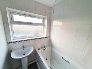 a white bathroom with a sink and a window at Owl Haven: Comfortable central 3 bedroom house, with an enclosed garden. in Bicester