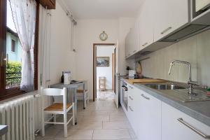 eine Küche mit weißen Schränken, einem Waschbecken und einem Fenster in der Unterkunft Villa Carolina in San Felice del Benaco