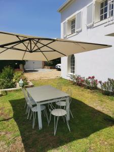 einen Tisch und Stühle unter einem Regenschirm im Hof in der Unterkunft Villa Via serena in Ajaccio