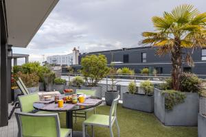 taras ze stołem i krzesłami na balkonie w obiekcie ILLANKA - Appartement 3 chambres avec parking et terrasse proche gare w mieście Rennes