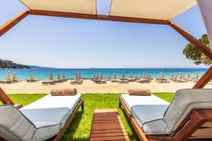 a view of a beach with lounge chairs and umbrellas at Ammoa Luxury Hotel & Spa Resort in Nikiti