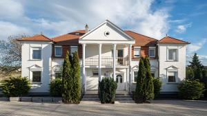 a large white house with a porch on a street at Villa Lilith Smart in Fertőrákos