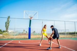 a man and a woman playing basketball on a court at Ammoa Luxury Hotel & Spa Resort in Nikiti