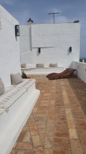 a patio with two white benches on a white wall at Hospedería Boutique Albariza by La Judería De Vejer- ADULTS ONLY in Vejer de la Frontera