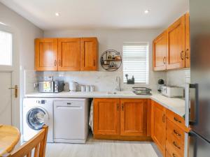 a kitchen with wooden cabinets and a white dishwasher at Broadway Cottage in Lincoln