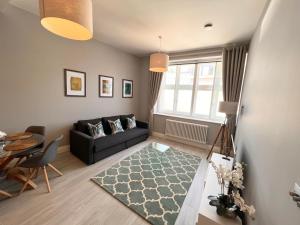 ein Wohnzimmer mit einem schwarzen Sofa und einem Tisch in der Unterkunft Urban Living's - Windsor Castle Luxury Apartments in Windsor