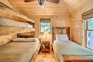two beds in a cabin bedroom with wooden walls at Lakefront Cottage Boat Dock, Patio and Kayaks! in Oxford
