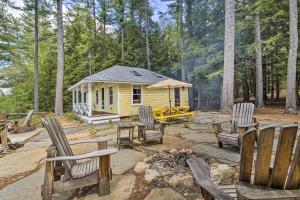 a small yellow cabin in the woods with chairs at Lakefront Cottage Boat Dock, Patio and Kayaks! in Oxford