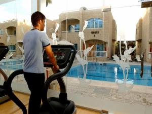 Verona Resorts Sharjah في الشارقة: رجل يركض على آلة ركض أمام حمام السباحة