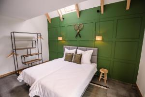 a bedroom with green walls and a white bed at Apartamenty Na Potokach in Żegocina