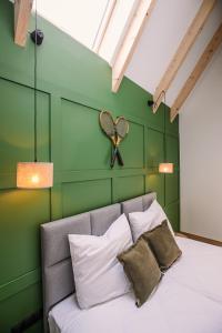 Un dormitorio con una pared verde y una cama con almohadas en Apartamenty Na Potokach, en Żegocina