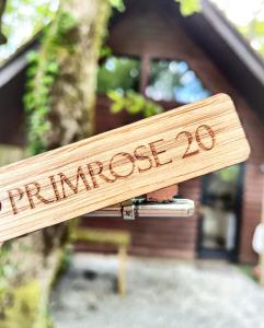 un cartel de madera que dice "pineose" sentado frente a una casa en Primrose 20-Woodland Lodges-Carmarthen-Pembroke, en Carmarthen