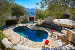 a swimming pool in a yard with chairs and an umbrella at Villa Del Sol - Scopello-Villas in Scopello