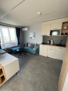 a living room with a blue couch and a kitchen at Апартаменти Генезис Ахтопол in Ahtopol